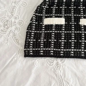 Detailed view of baby knitwear showcasing black and white tweed pattern with contrast pockets.