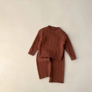 Detail des Strickpullover-Sets für Babys, weicher terracottafarbener Zopfstrick, kuschelige Hosen.
