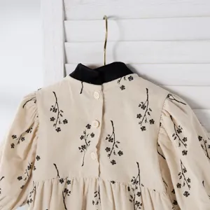 Close-up detail of infant baby girl floral romper with contrast black collar and puff sleeves.