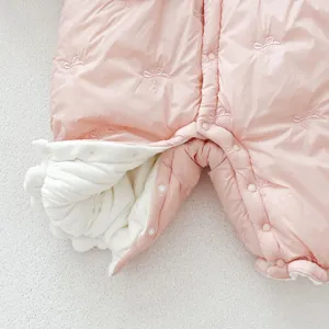Close-up of pink quilted baby winter romper with bow embroidery and warm lining detail.