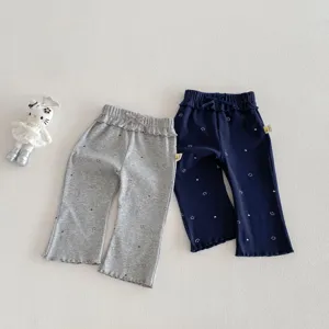 Détail pantalon évasé imprimé smiley mignon, taille à nœud et volants pour bébé fille.