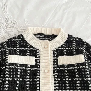 Black and white tweed knit cardigan detail, elegant baby girl sweater trim, soft cotton fabric.