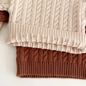 Nahaufnahme der Textur des Babypullovers mit Zopfmuster, weicher Stoff, gemütliches Design.