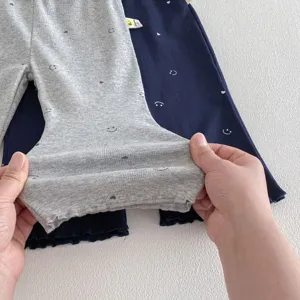 Détail de pantalon évasé en coton pour bébé montrant un tissu extensible et imprimé.