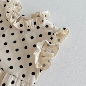 Infant sleeveless romper detail, beige polka dot fabric, cute ruffled collar design.