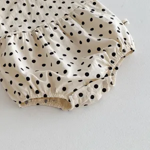 Detail shot of cotton baby infant polka dot romper bodysuit with cute ruffles and buttons.
