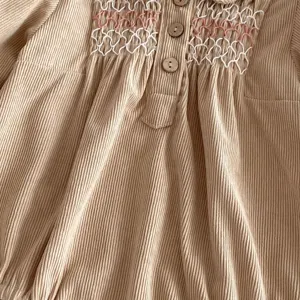Baby corduroy romper detail, cute infant smocked bodysuit with stylish wooden buttons.
