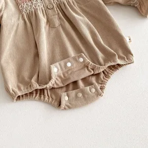 Infant baby girl corduroy romper detail view, sweet smocked embroidery and snap button design.