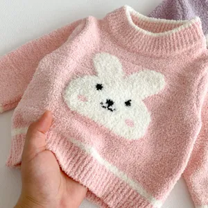 Close-up of fluffy pink baby sweater featuring cute white rabbit applique and soft fleece texture.