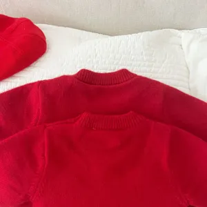 Close-up detail shot showing the collar and soft fabric texture of the red knit sweater.