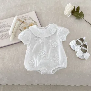 Detailed shot of infant white baby girl romper with doll collar, floral cut-work and short sleeves.