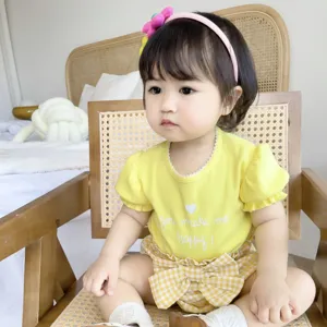 Vue détaillée de la tenue d'été bébé fille, top jaune et short à carreaux, cadre chaleureux