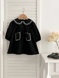 Abito nero a maniche lunghe per neonata con colletto e tasche ricamati in bianco, delizioso.