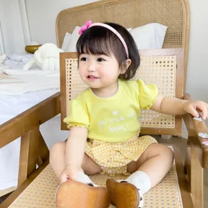 Vue détaillée adorable tenue été bébé fille, haut jaune imprimé cœur, short carreaux.