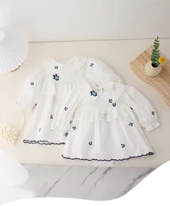Dettaglio vestito tutina manica lunga neonata bianco con ricamo floreale blu delicato.