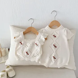 Knit baby clothes detail view showing delicate handmade crochet embroidery and soft texture.