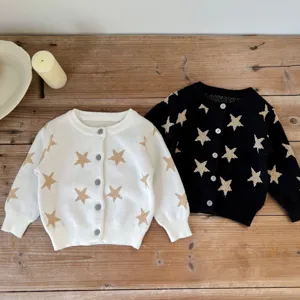 Detailed shot of baby cardigan sweater with gold star patterns on soft knit fabric surface.