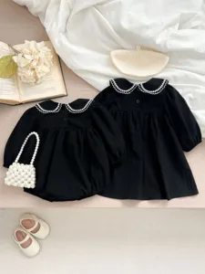 Vista dettagliata del vestito nero a maniche lunghe da bambina con delizioso colletto in pizzo.