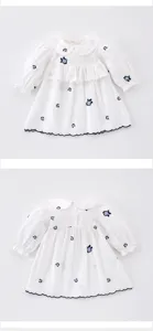 Vista dettagliata del vestito da bambina bianco a maniche lunghe con ricamo floreale e colletto.