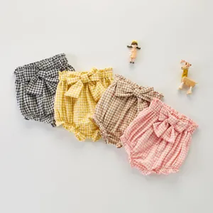 Détails en gros plan de culottes courtes à carreaux pour bébés filles avec nœuds mignons.