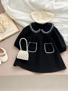 Abito nero a maniche lunghe per neonata con colletto bianco in pizzo e tasche decorative.