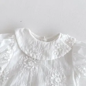 Close-up detail of white baby girl short sleeve embroidered doll collar romper and crawler.