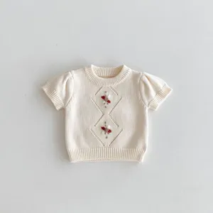 Detailed view of baby knit short-sleeve top, soft cotton fabric with delicate embroidery.