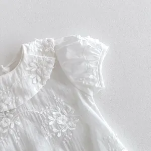 Close-up detail of white baby girl short-sleeve romper with delicate embroidery doll collar.