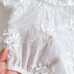 Baby girl romper fabric detail featuring delicate white floral embroidery and texture.