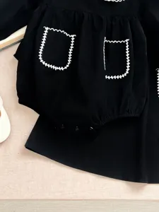 Tutina neonata nera a maniche lunghe con tasche ricamate in bianco, grazioso body.