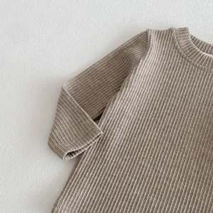 Gros plan sur un haut bébé à manches longues en tricot côtelé, couleur taupe neutre.