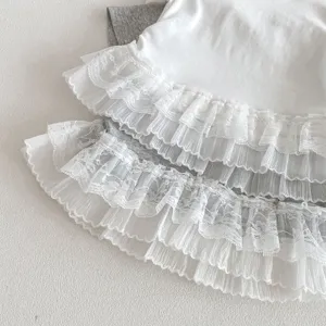 Filles haut à volants de dentelle superposés gros plan, détail t-shirt blanc gris, vêtement enfant.