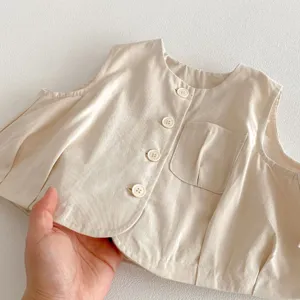 Détail du gilet pour bébé beige clair montrant le tissu doux et les poches fonctionnelles.