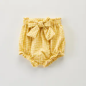 Détail de short bébé vichy jaune et blanc, nœud adorable et taille élastique douce.