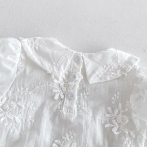 White baby romper detail shot, showcasing delicate floral embroidery and sweet doll collar style.