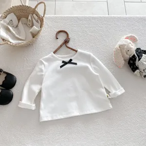 Toddler white long sleeve t-shirt close up, featuring a cute black bow detail at the collar.