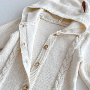 Cream knit baby romper detail, cozy hooded jumpsuit with cute bear ears and wood buttons.