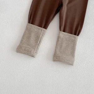 Détail de pantalon bébé nourrisson, poignets côtelés contrastés sur leggings marron.
