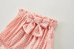 Gros plan détaillé du short bloomer bébé à carreaux rose avec un très joli nœud sur la taille.
