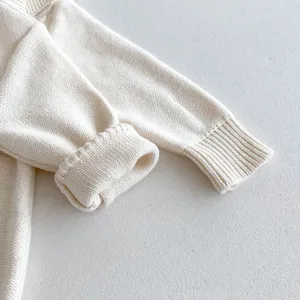 Close-up detail of infant knitted sweater sleeve, soft cotton yarn material, fine texture.