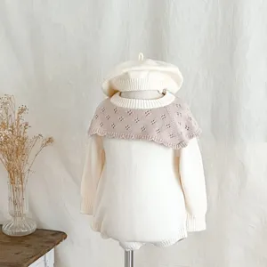 Vue détaillée de la combinaison tricotée pour bébé avec col volanté ajouré et béret assorti.