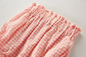 Détail gros plan de short bouffant bébé vichy rose, texture douce volant de taille.