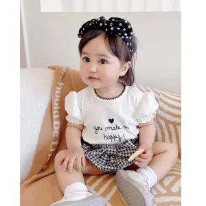 Adorable ensemble d'été pour bébé fille avec un t-shirt blanc et un short à carreaux.