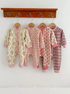 Detail view of cute baby knit rompers hanging on a rack, featuring charming floral and heart patterns.