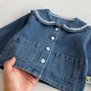 Baby denim jacket detail view showing soft fabric, sailor collar, and white button closure.
