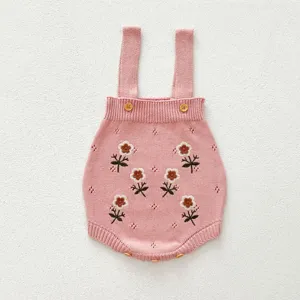 Primo piano dettagliato della tutina rosa per neonati con ricami floreali e bottoni.
