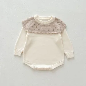 Détail de barboteuse en tricot bébé avec charmant col festonné ajouré et manches.
