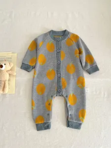 Detailed view of cute baby knit romper with orange print, cozy fabric, soft texture and buttons.