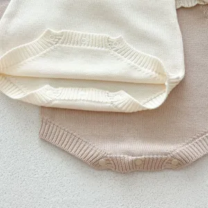 Gros plan détaillé d'un body bébé en tricot doux avec des boutons-pression pratiques en bas.