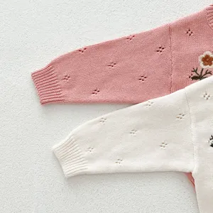 Vista dettagliata della manica del maglione in maglia da neonato con ricamo floreale.